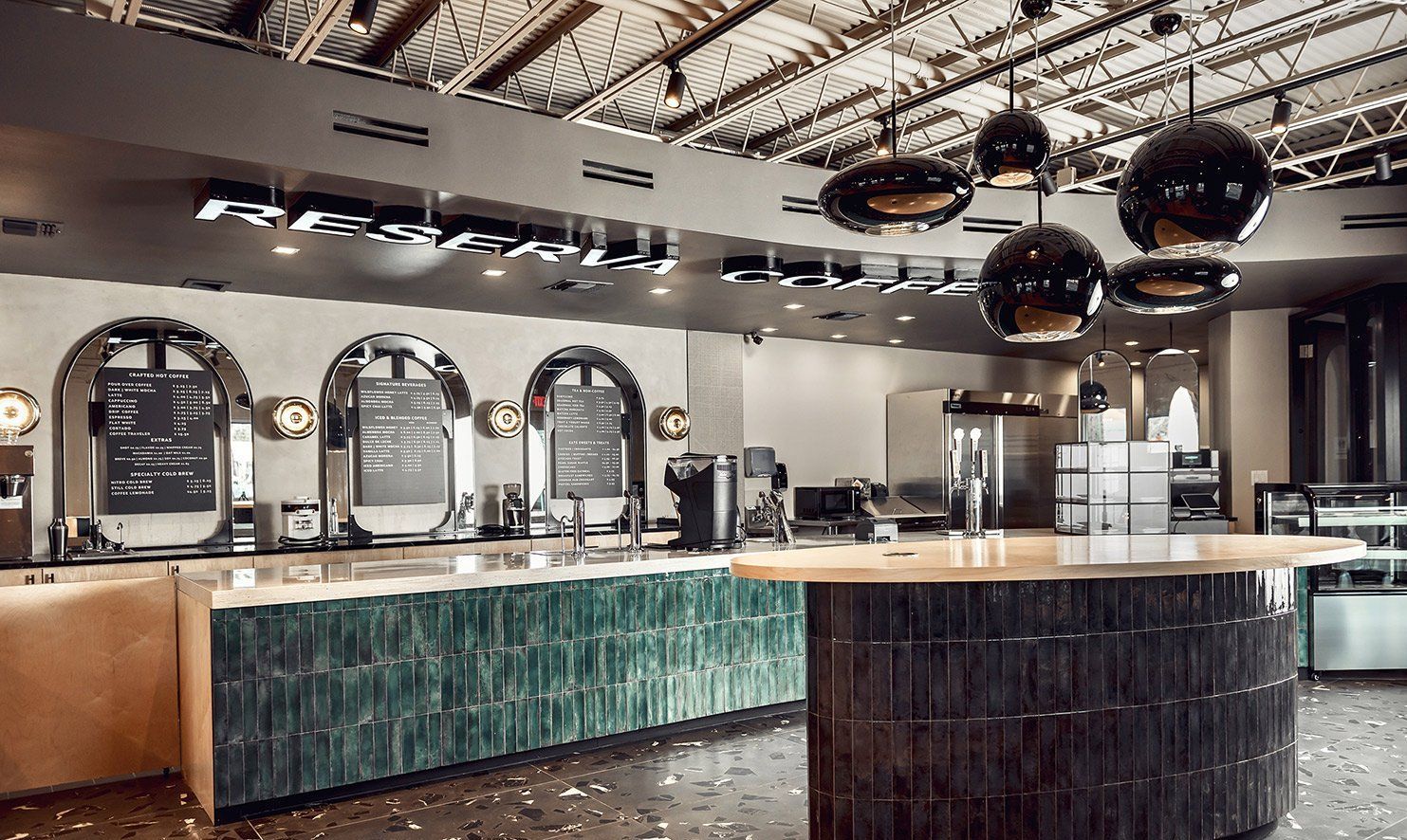 Modern bar with arched mirrors, polished counter, and hanging spherical lights in an industrial interior