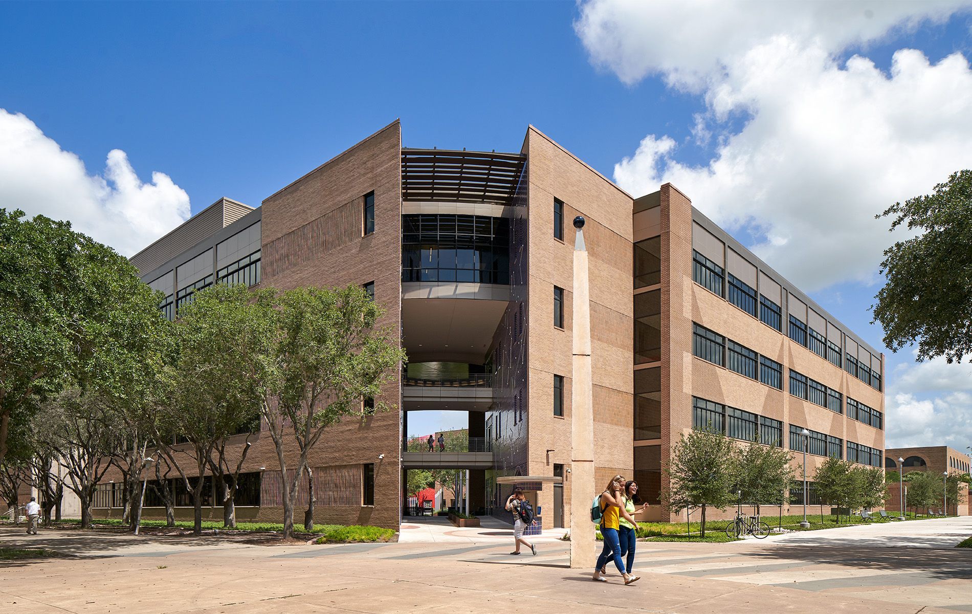 Modern brick campus building with students walking outside on a sunny day