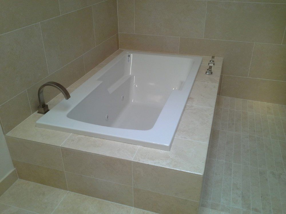 A bathtub is sitting on top of a tiled floor in a bathroom.