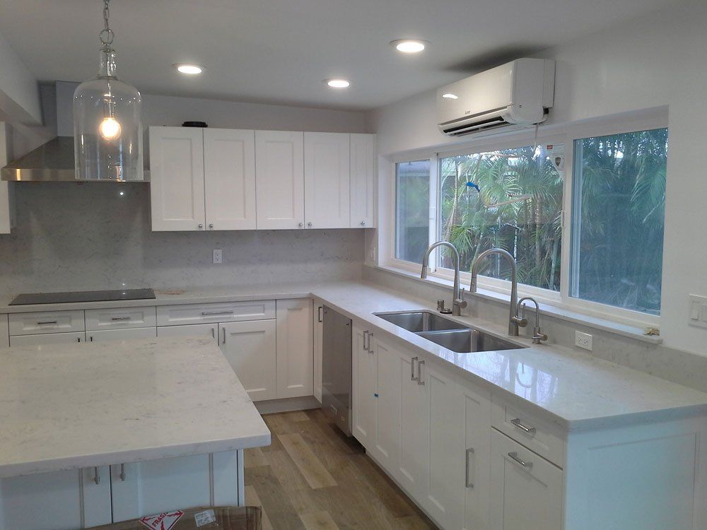 A kitchen with white cabinets , a sink and a window.
