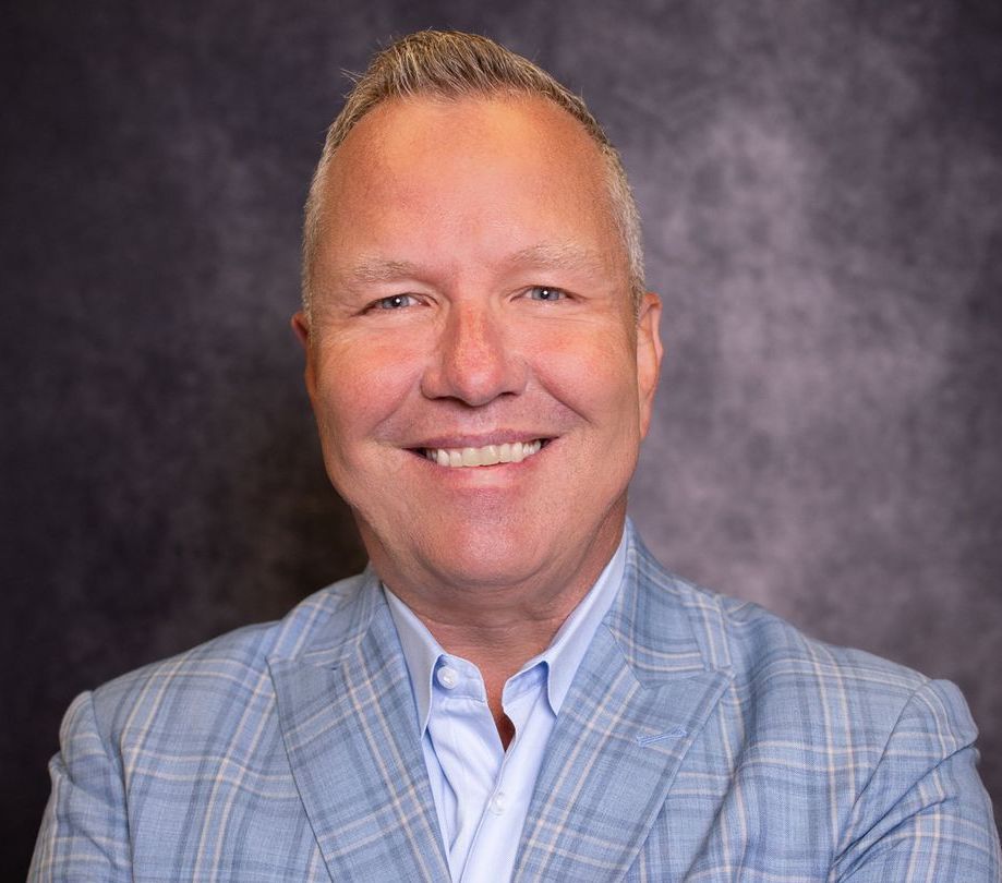 A man in a blue suit and white shirt is smiling for the camera.