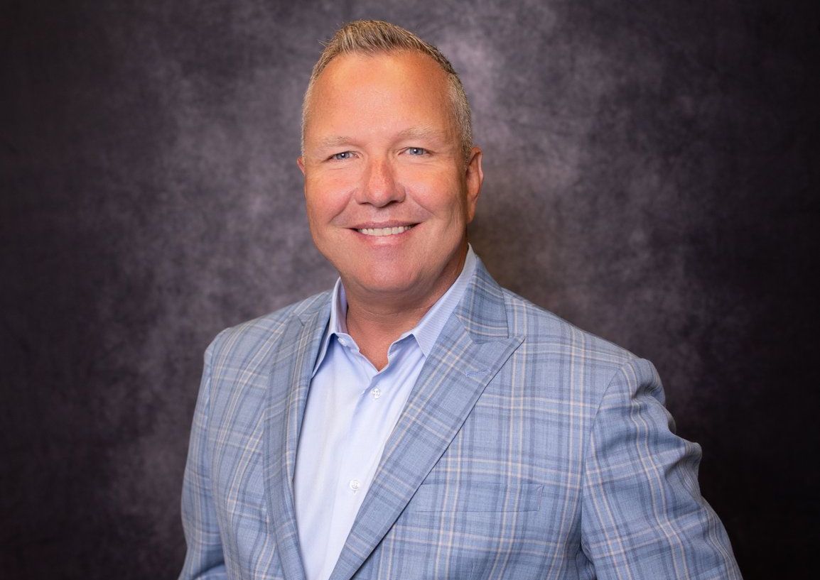A man in a blue suit and white shirt is smiling for the camera.
