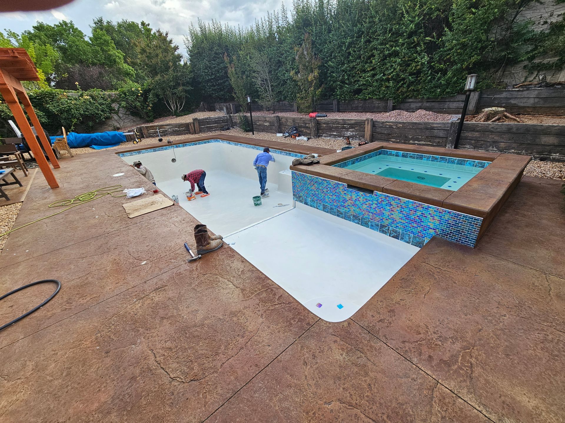 An indoor swimming pool with black lane markers, stone walls, a partially covered roof, and two foam exercise blocks.