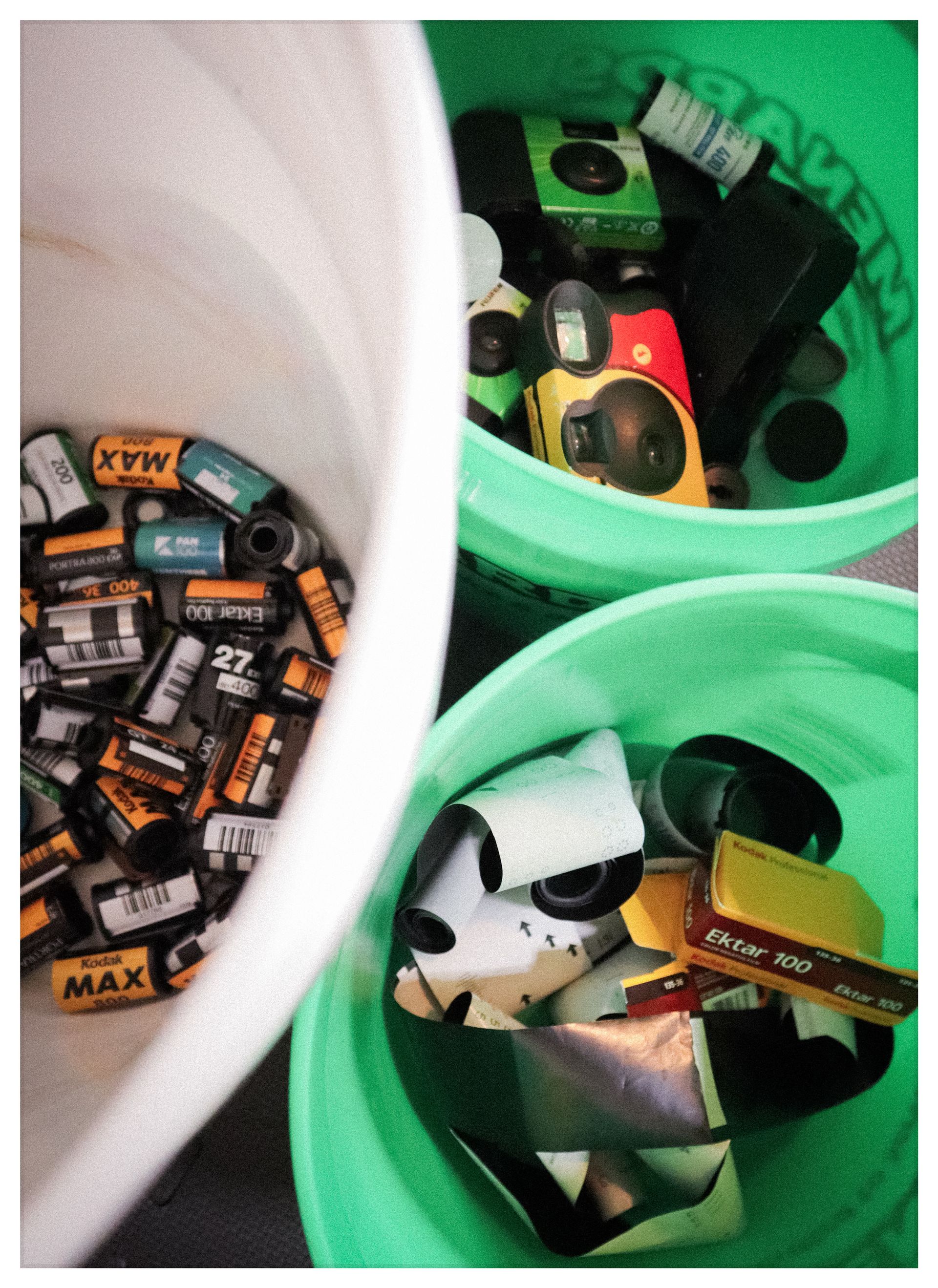 Battery recycling bins with assorted used batteries in white and green containers