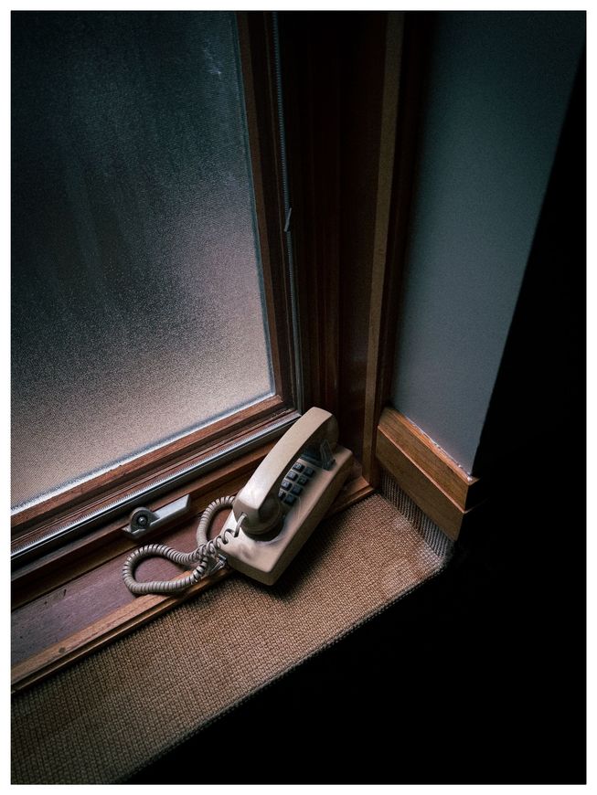Keys on a wooden windowsill beside a small black device in a dim corner.