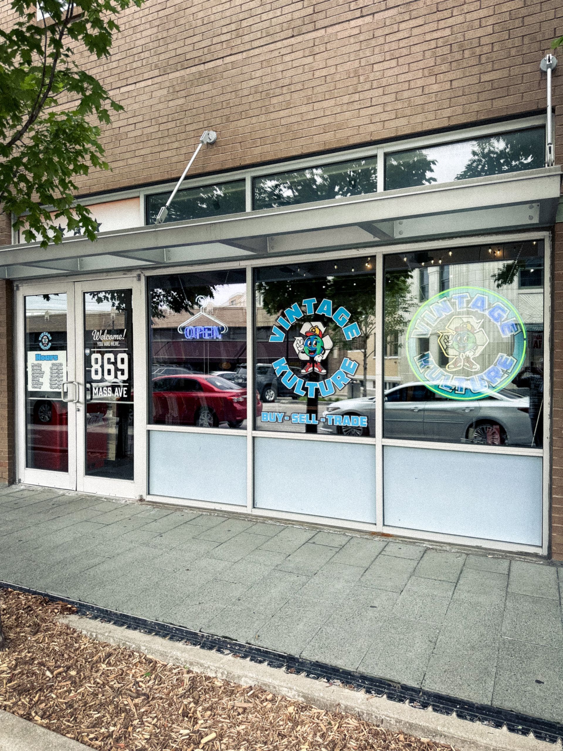 Storefront with glass windows, doors, and colorful circular decals on a brick building sidewalk