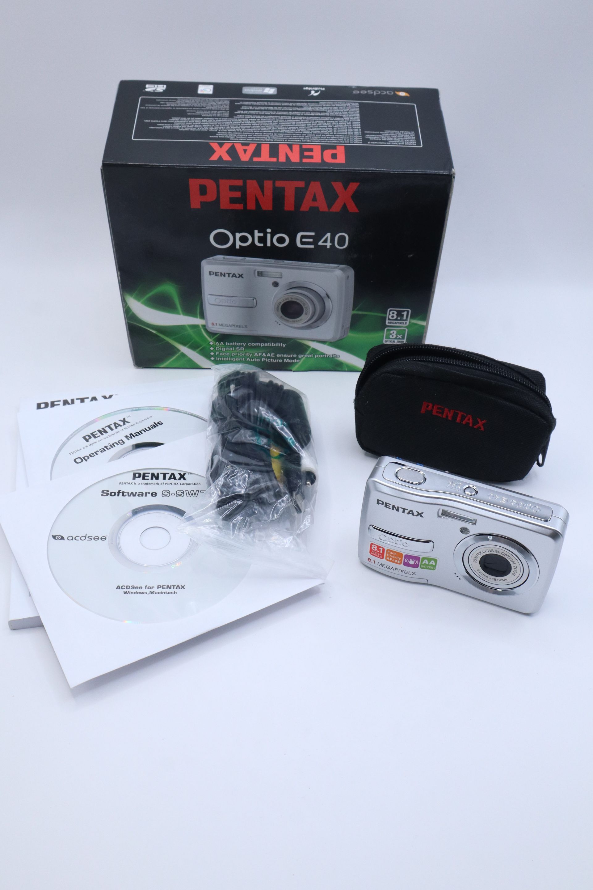 Pentax Optio E40 camera box with camera, battery charger, CD, cable, and case on a white surface