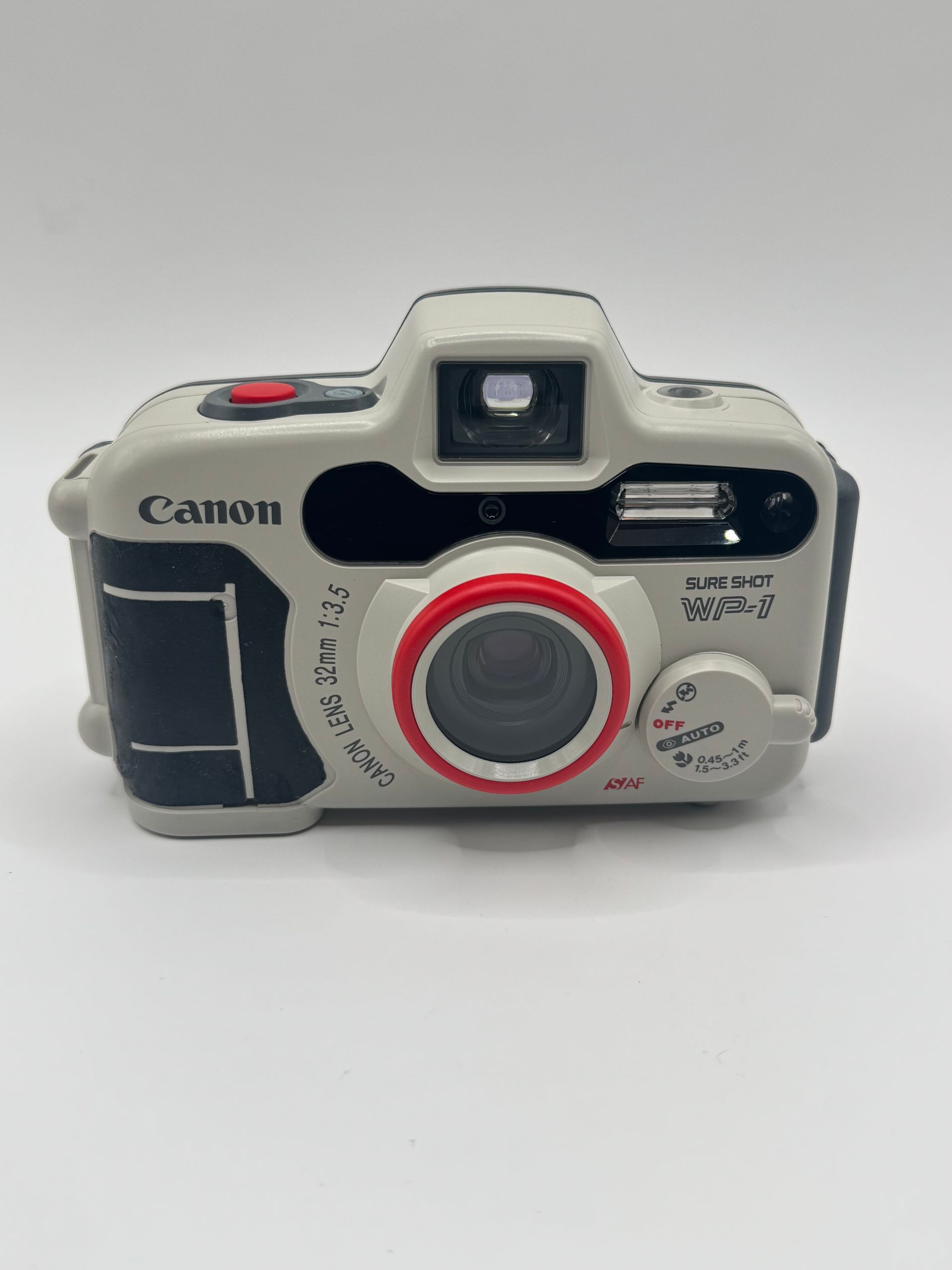 Canon Sure Shot film camera, silver with red accents, front view on white background