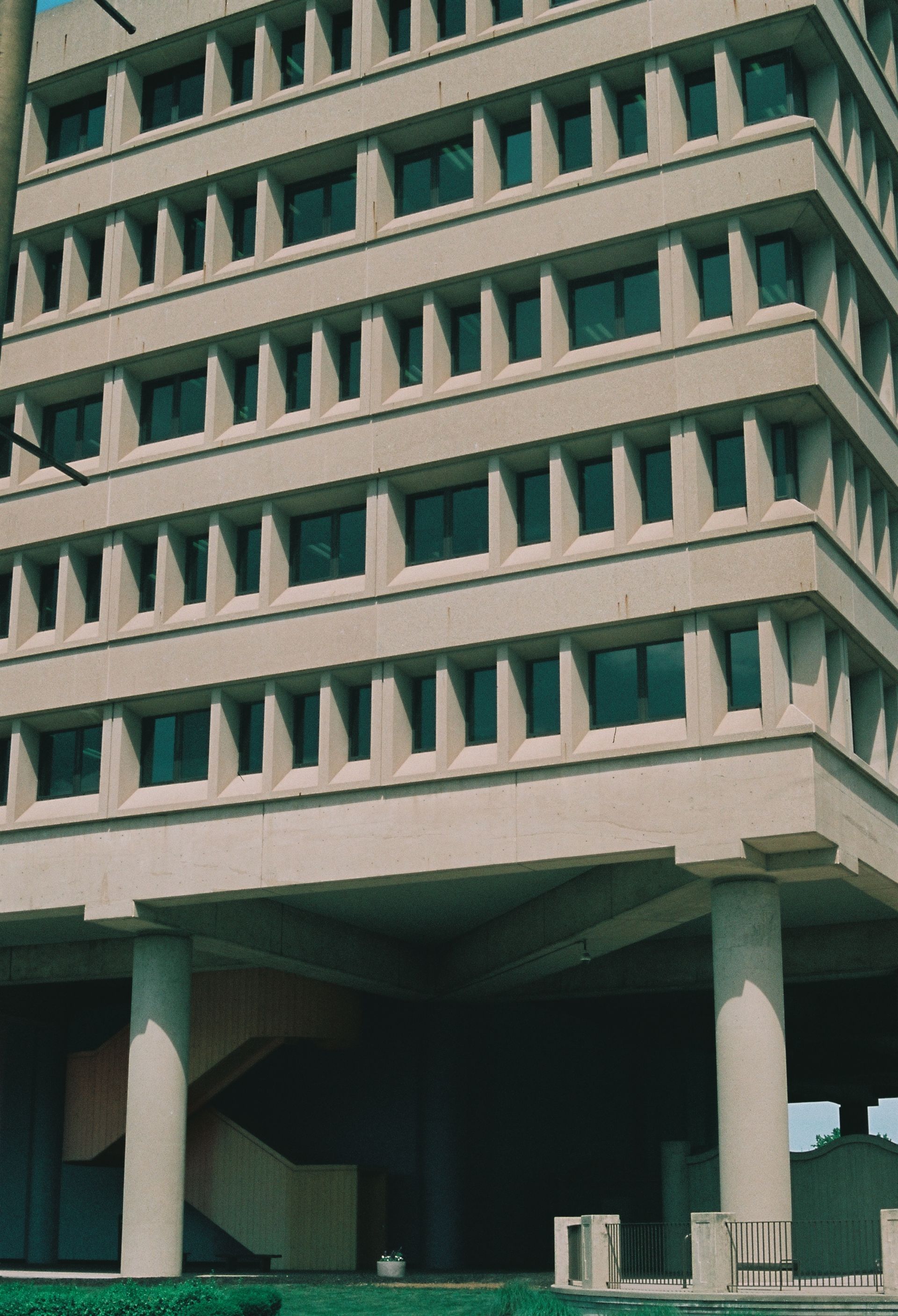 Tall concrete building with repeating triangular windows and columns at the base