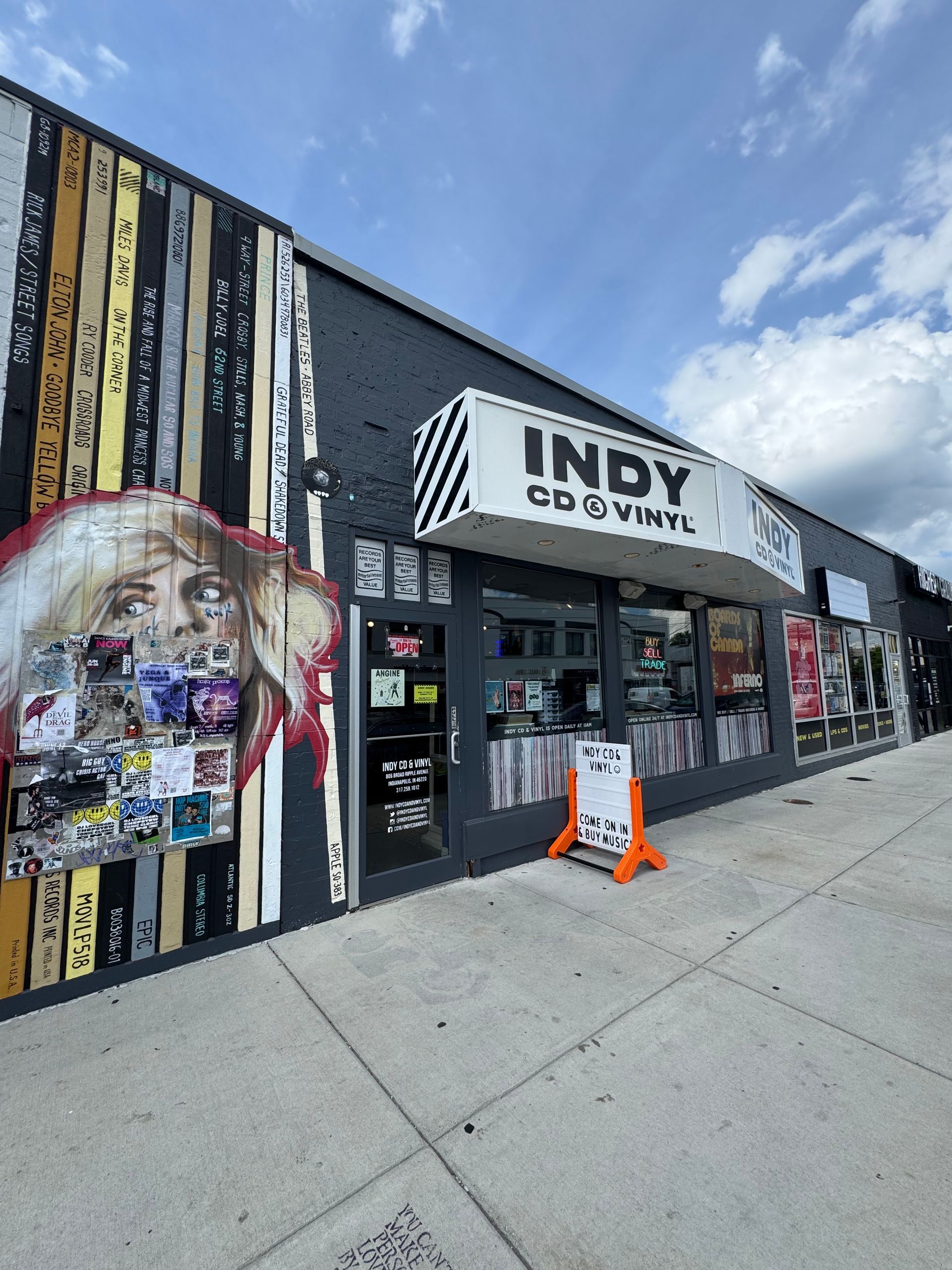 Storefront with glass windows, doors, and colorful circular decals on a brick building sidewalk