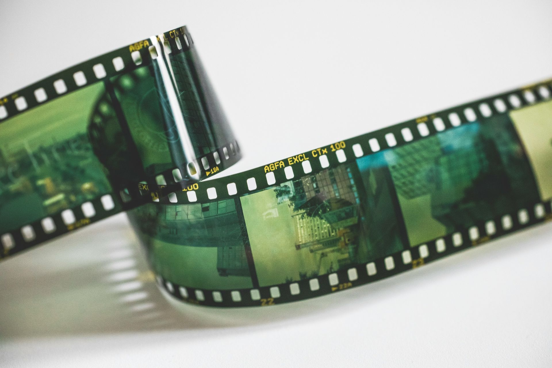 Green filmstrip with rolled frames on a white background