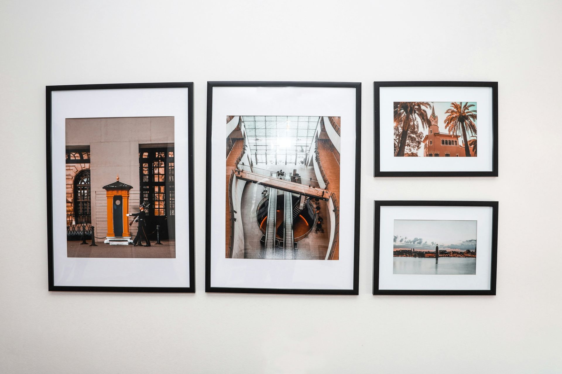 Three framed photos on a white wall, including an orange doorway, a bridge view, and two smaller landscape prints