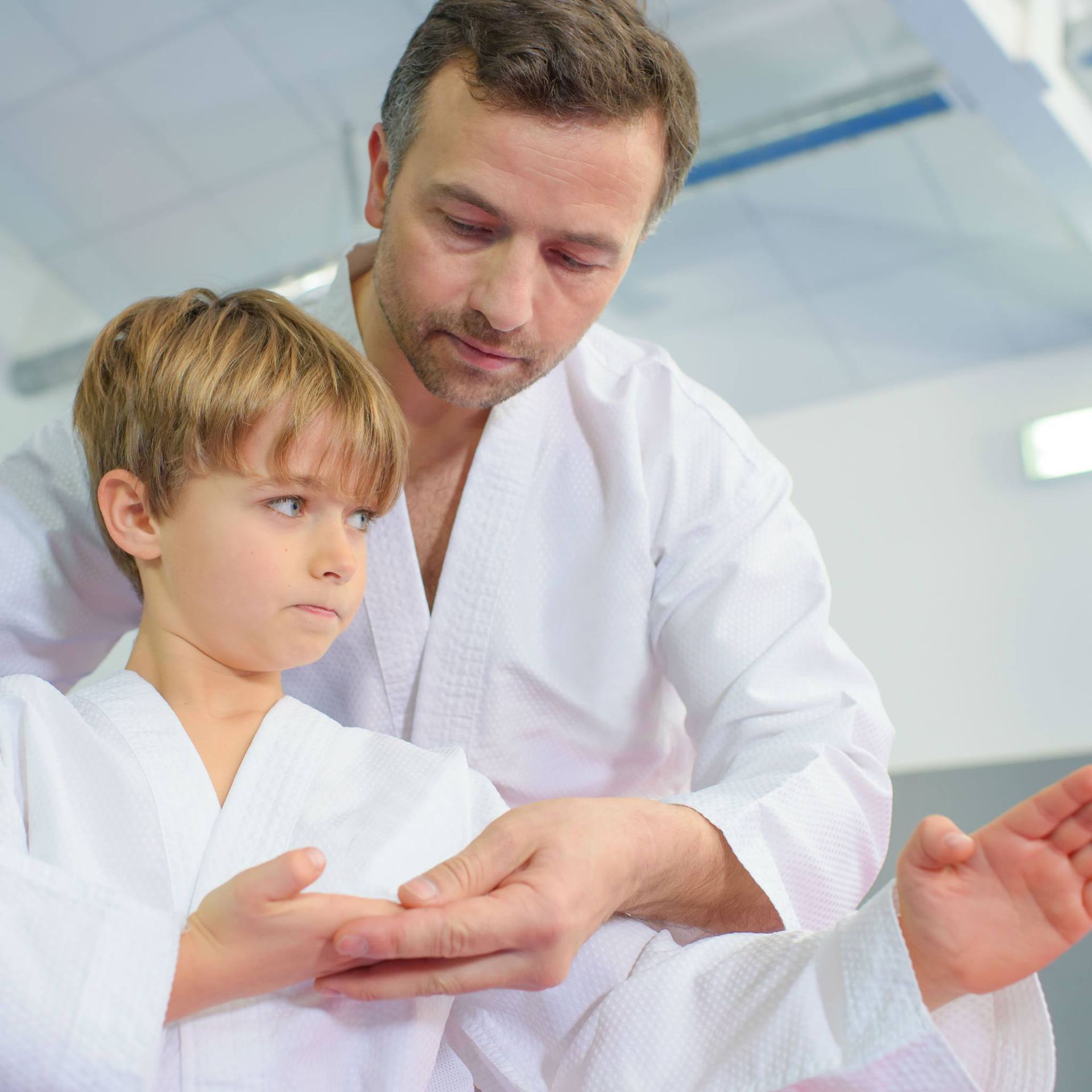 A man is teaching a young boy how to do karate.