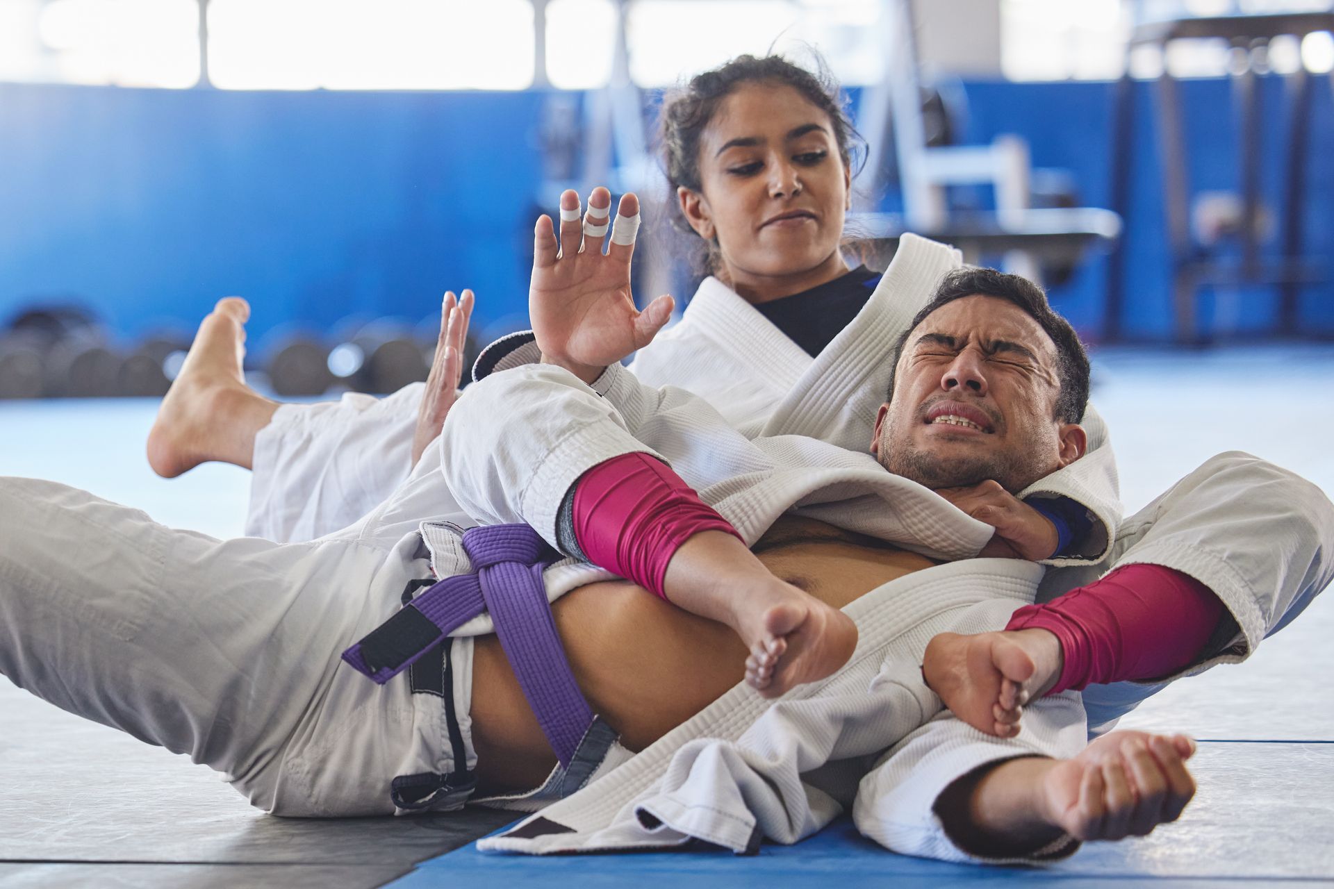 a man and a woman are wrestling on a mat in a gym .