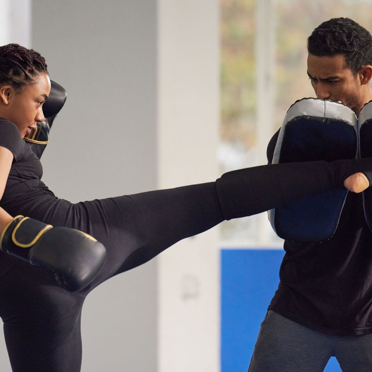 A man and a woman are boxing in a gym.