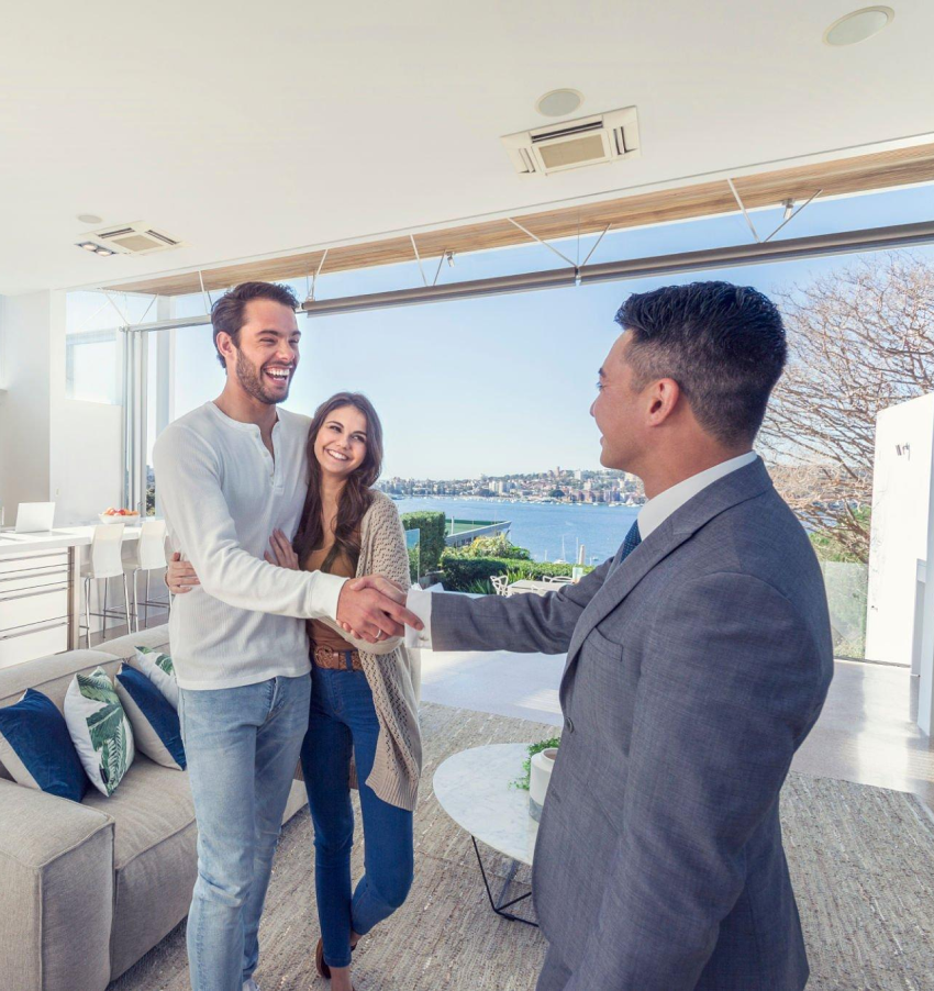 A man in a suit shakes hands with a woman in a living room