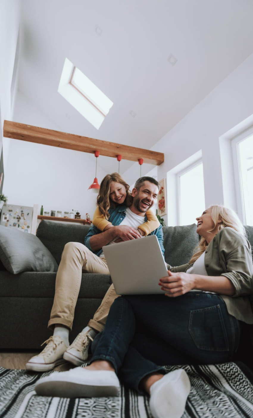 A family is sitting on a couch using a laptop computer.