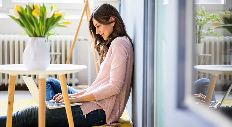 A woman is sitting on the floor using a laptop computer.