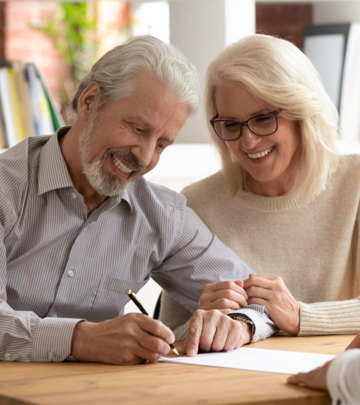 A man and a woman are sitting at a table writing on a piece of paper.