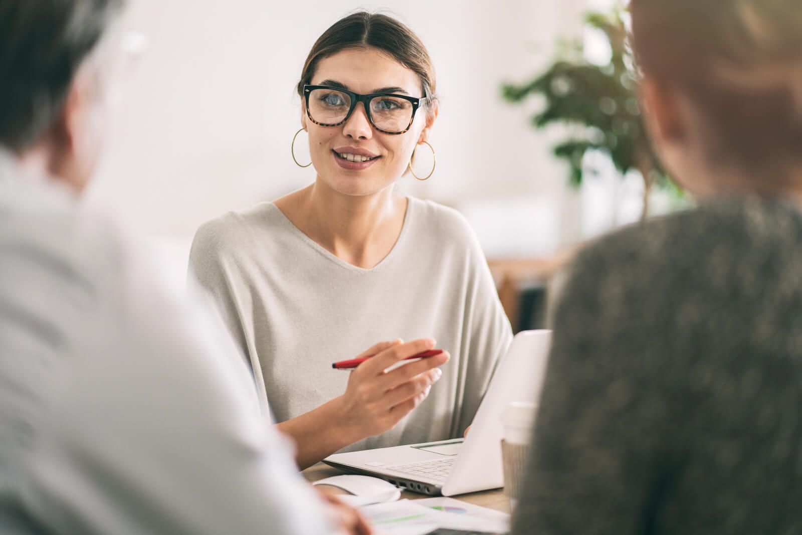 A woman is sitting at a table talking to two people.