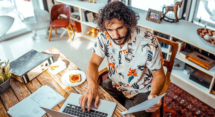 A man is sitting at a table using a laptop computer.