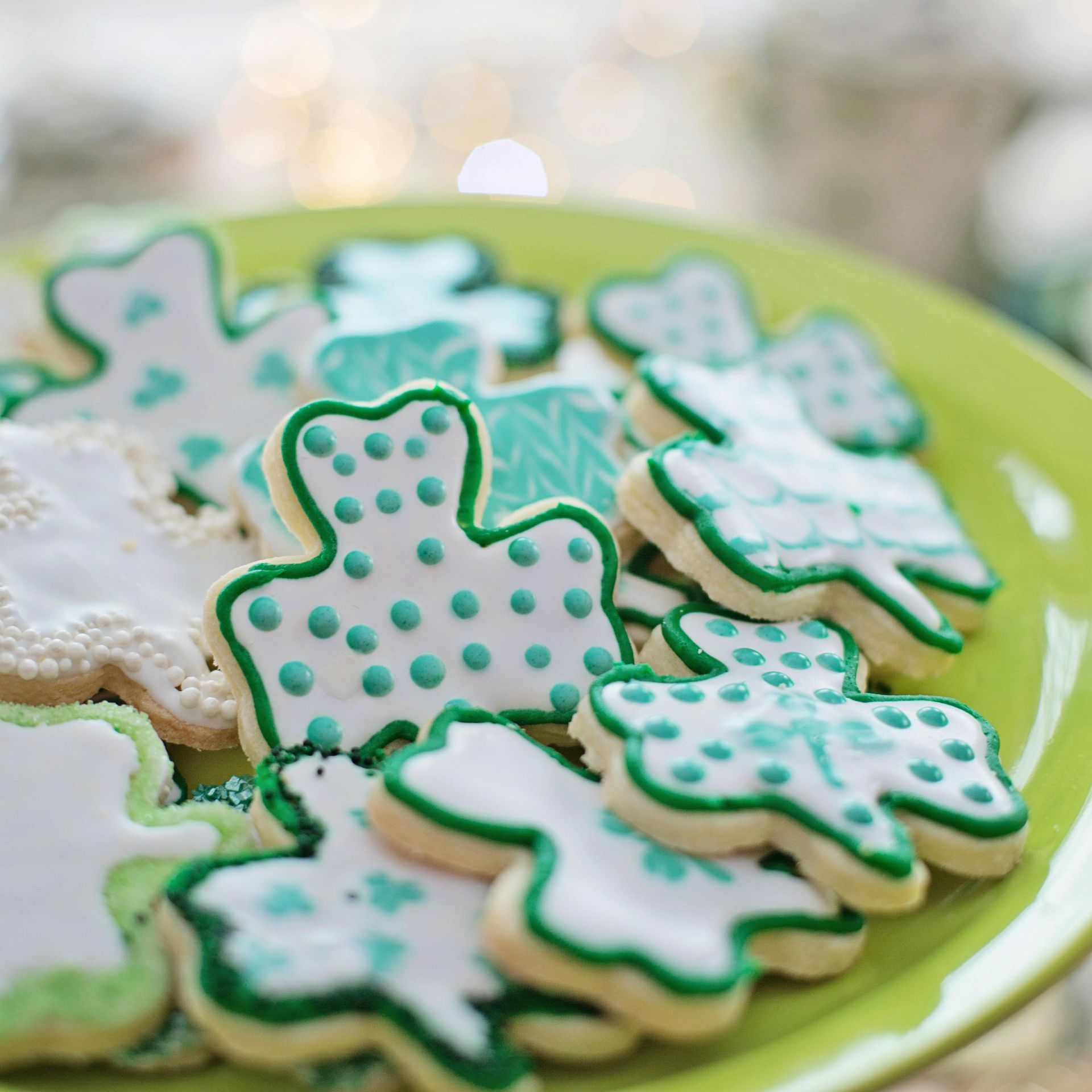 A green plate topped with green and white cookies in the shape of shamrocks