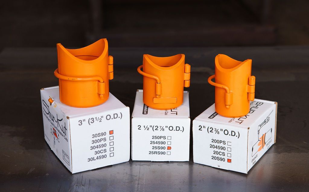 Three orange plastic connectors on labeled white boxes on a table.