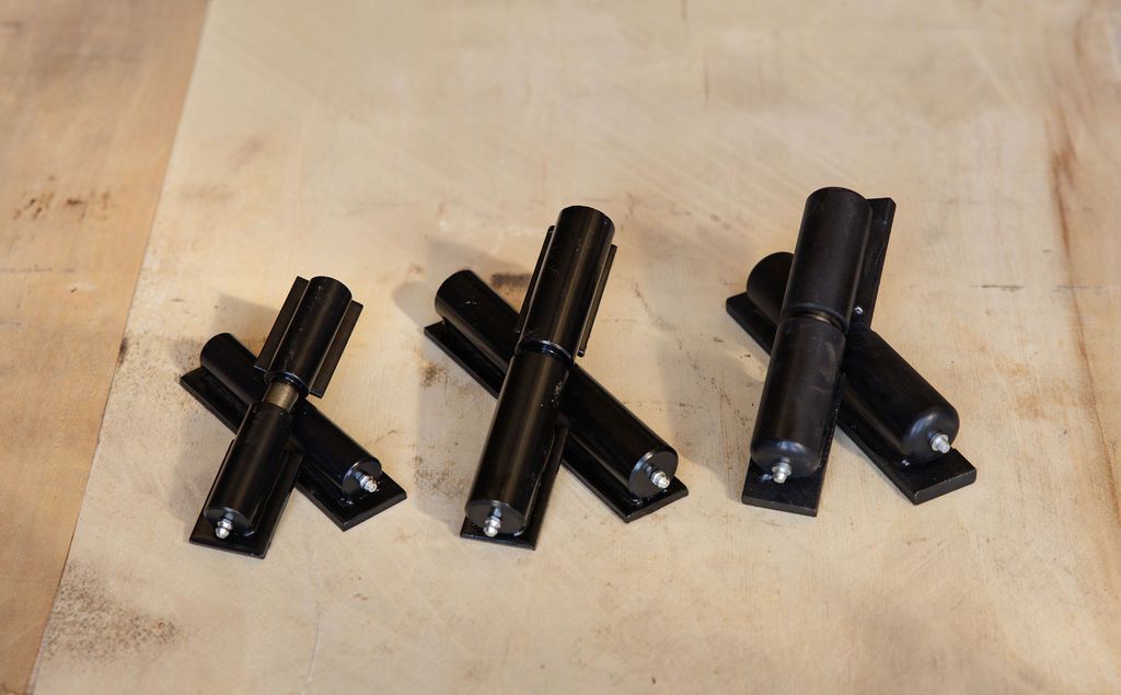 Three black metal brackets arranged on a light wooden surface.