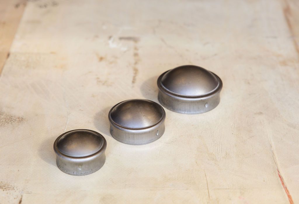 Three small metal cups or molds arranged diagonally on a light wooden surface.