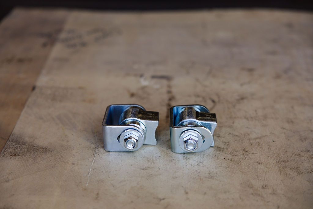 Two small silver metal clamps on a worn wooden surface