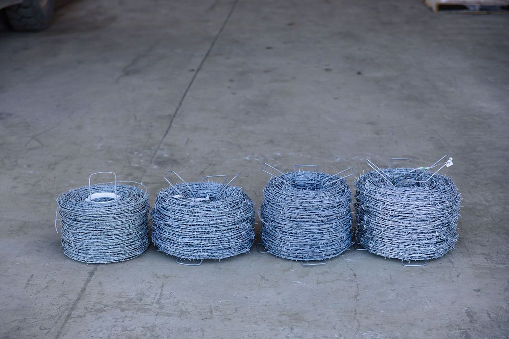 Four blue-gray coiled wire bundles lined up on a concrete floor