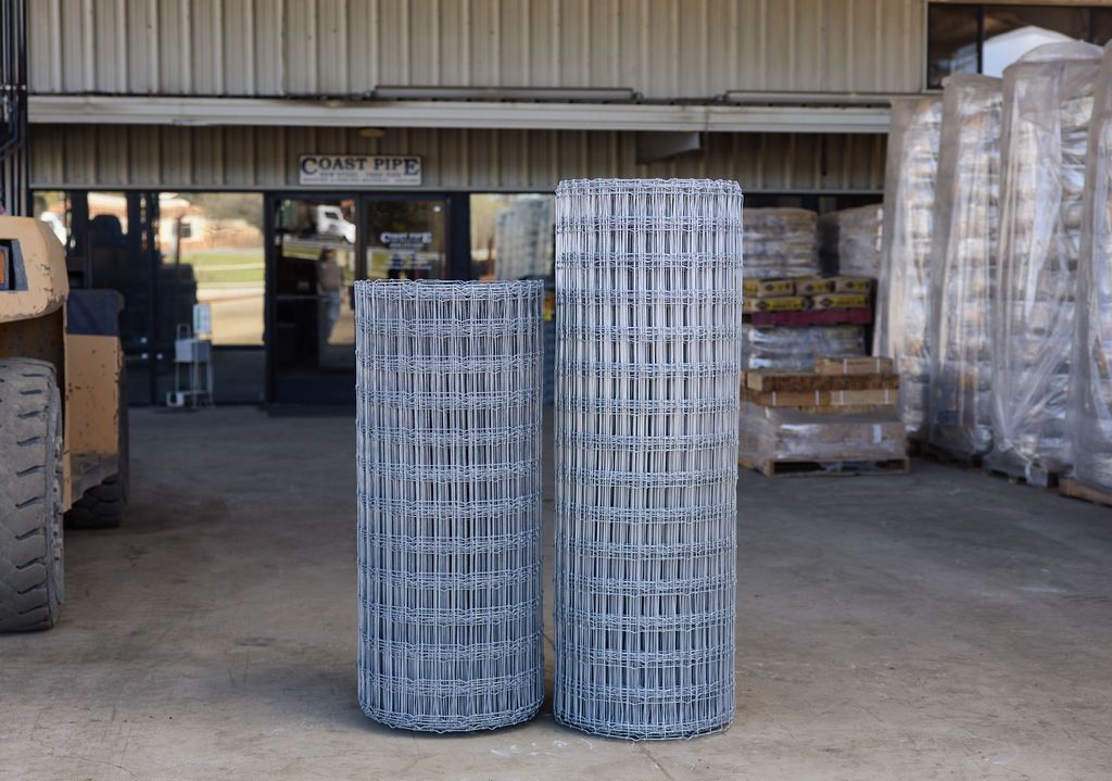 Stacks of silver wire mesh rolls in a warehouse loading area.