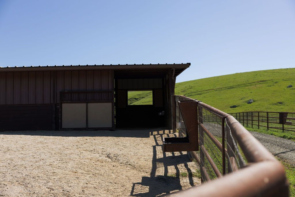 Farm shed beside a fenced grassy field under a clear blue sky