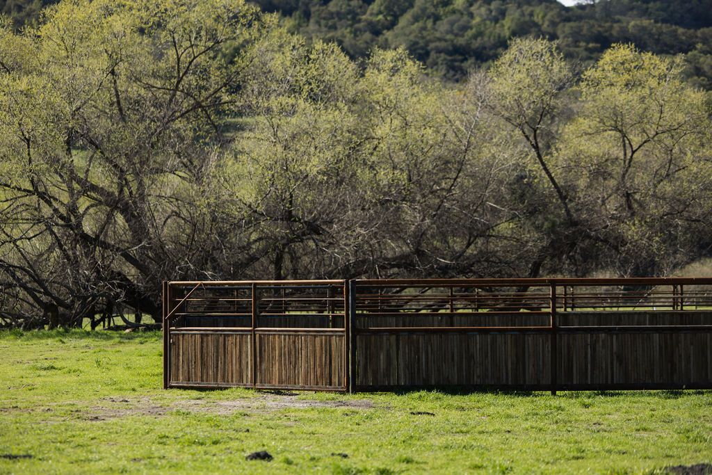 Wooden fence in a grassy field with trees and hills in the background