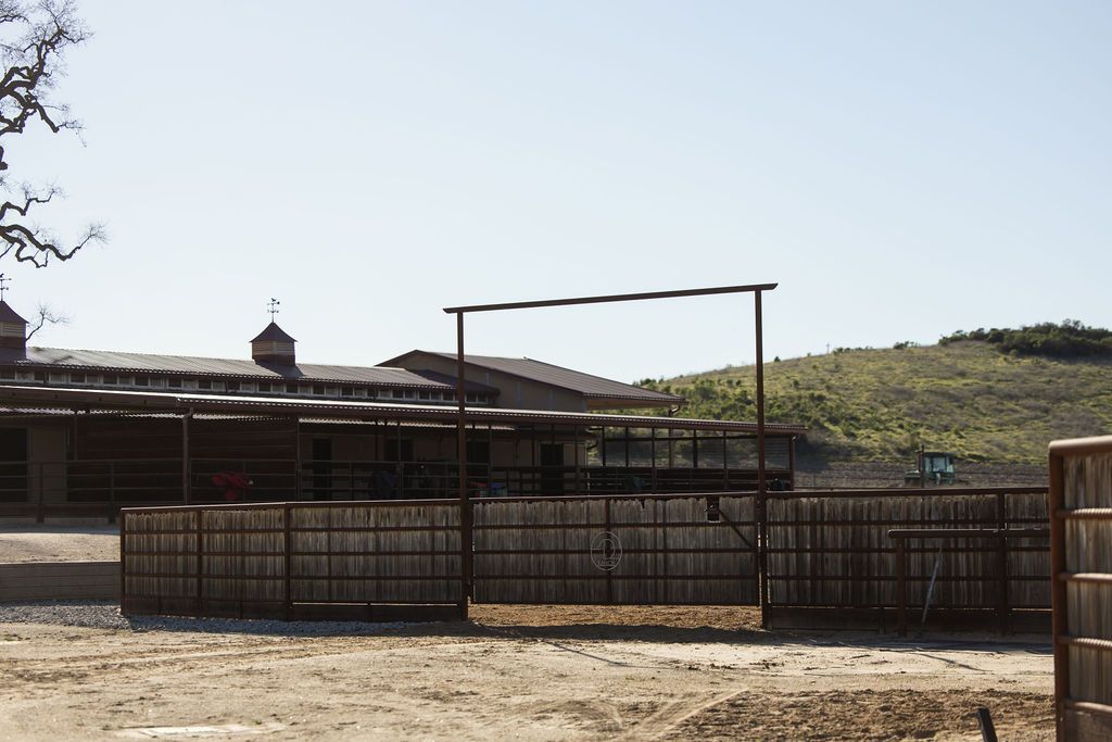 Empty fenced livestock pen in a dusty outdoor corral with hills in the background