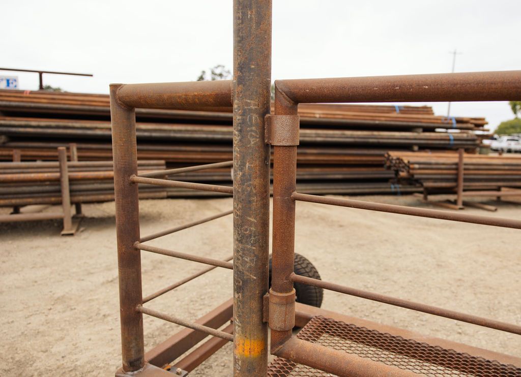Rusty metal pipe rack at an industrial yard with stacked pipes in the background