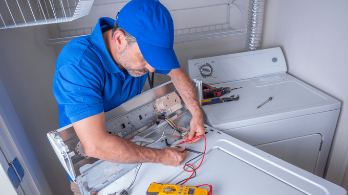 “Repair technician in a blue cap working on the control panel of a washing machine during an appliance repair service in Taylorsville, UT”