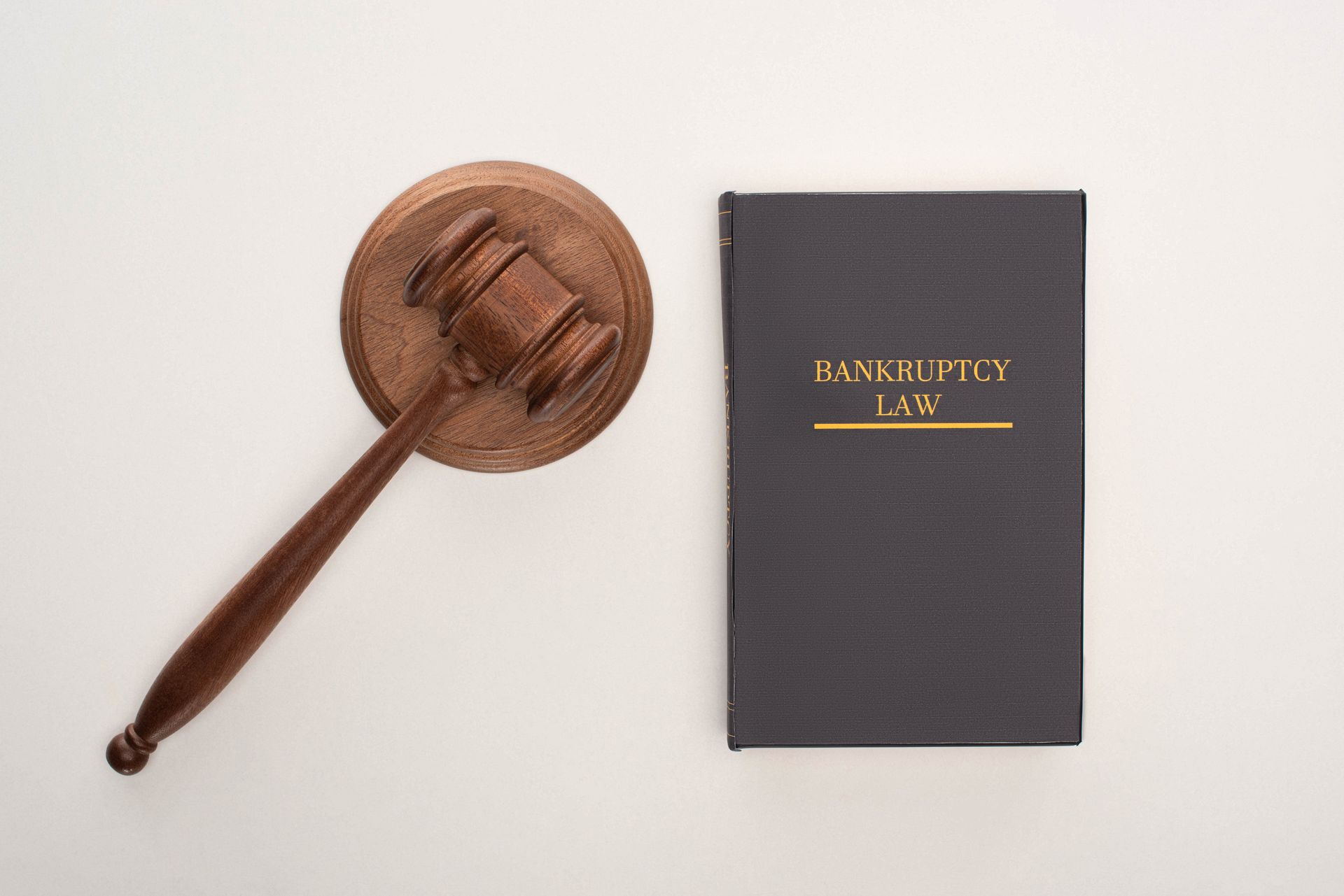 Gavel on wooden base next to a book titled