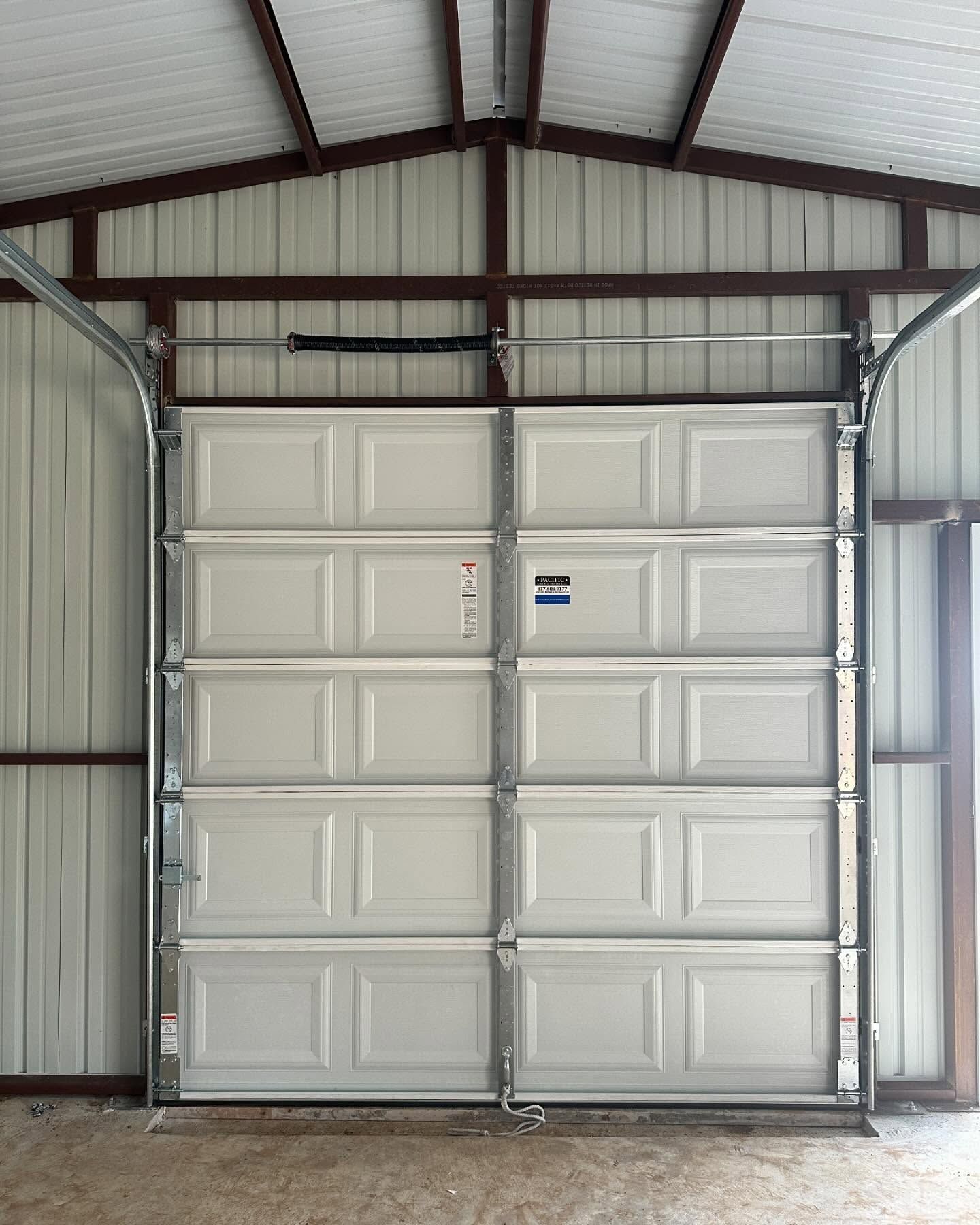 A white garage door is open in a garage