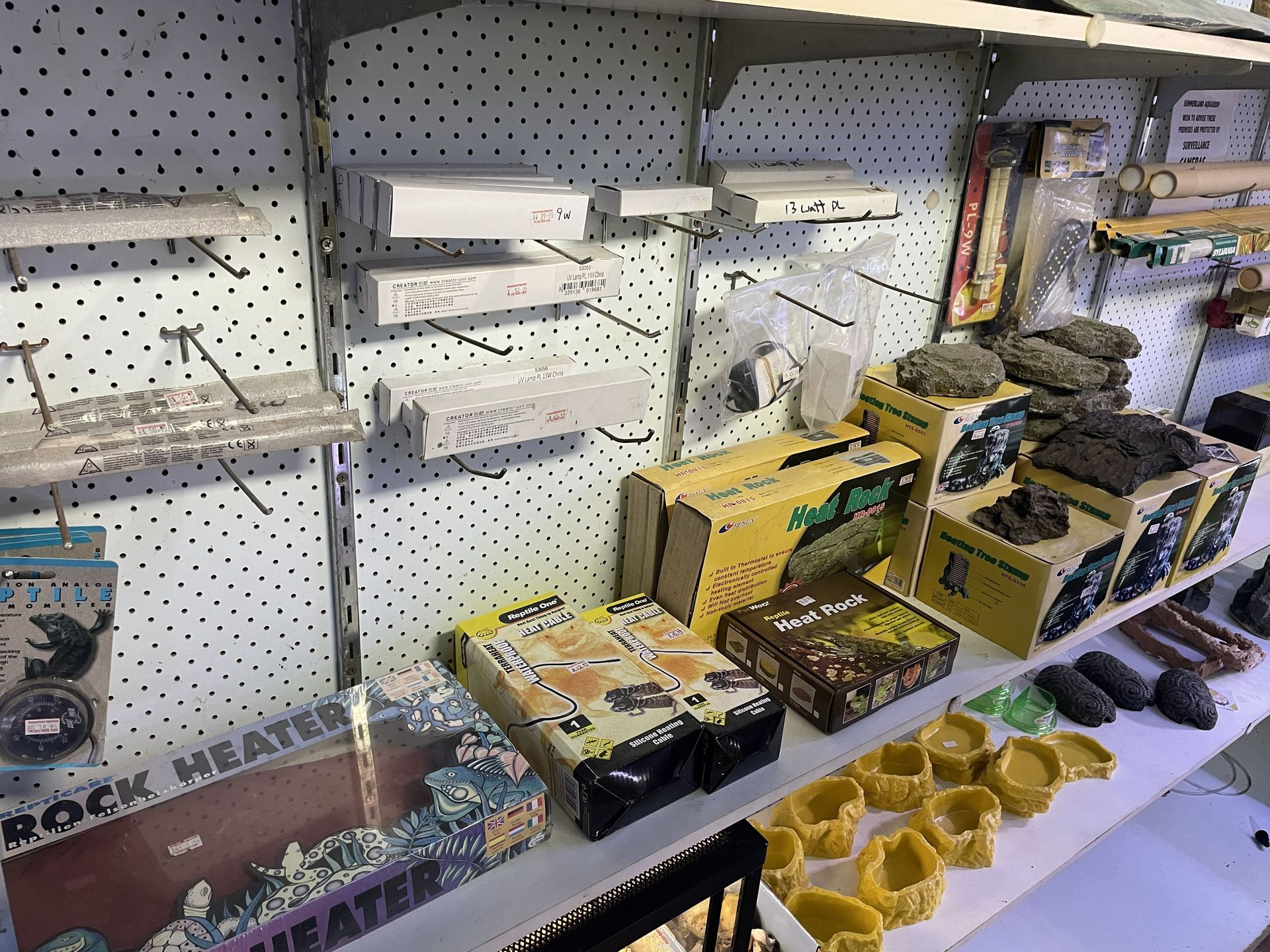 Shelves stocked with pet supplies, including heating elements and rock decor.