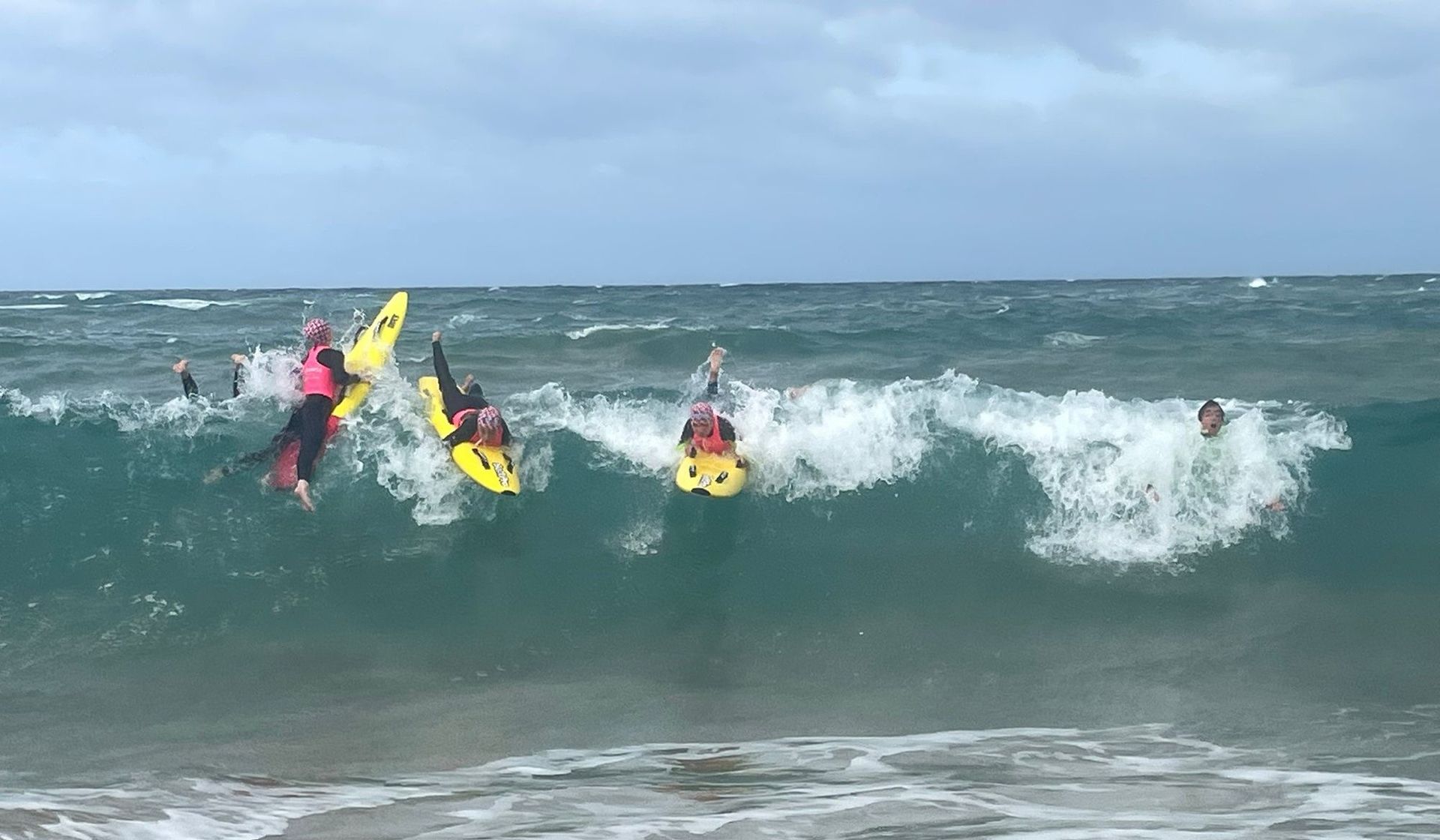 Nippers riding foam boards through the whitewater.