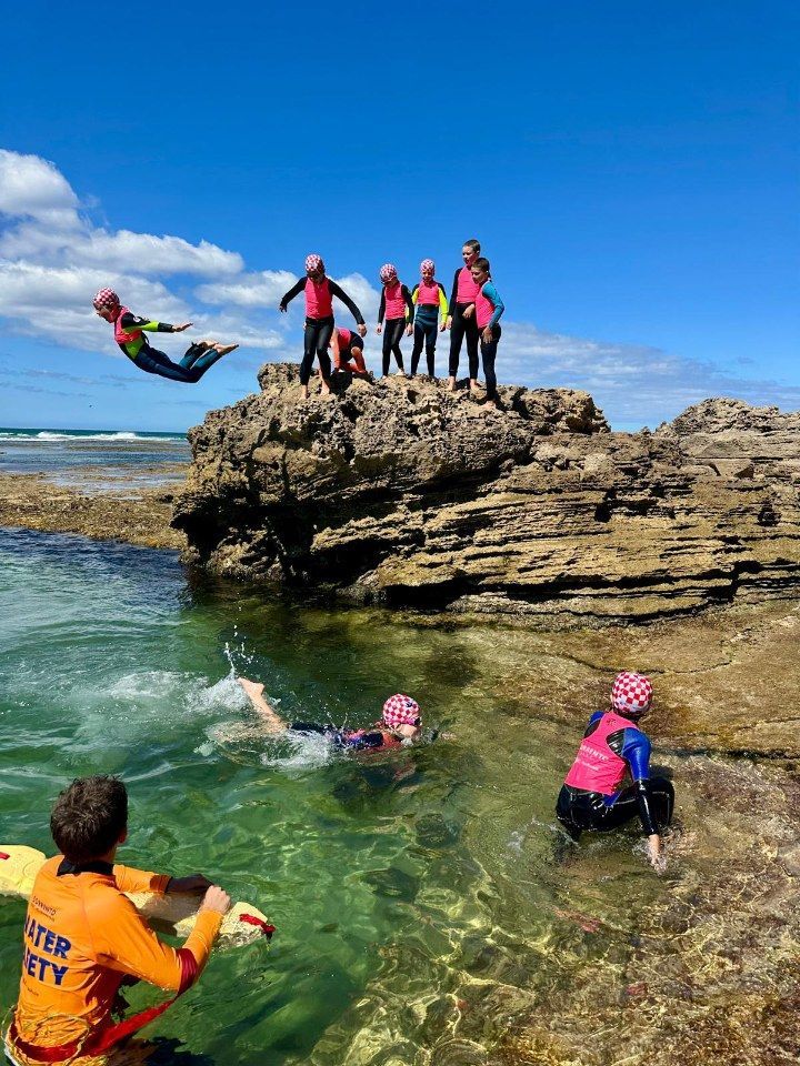 Nippers snorkelling in a shallow rock pool with a water safety volunteer supervising.