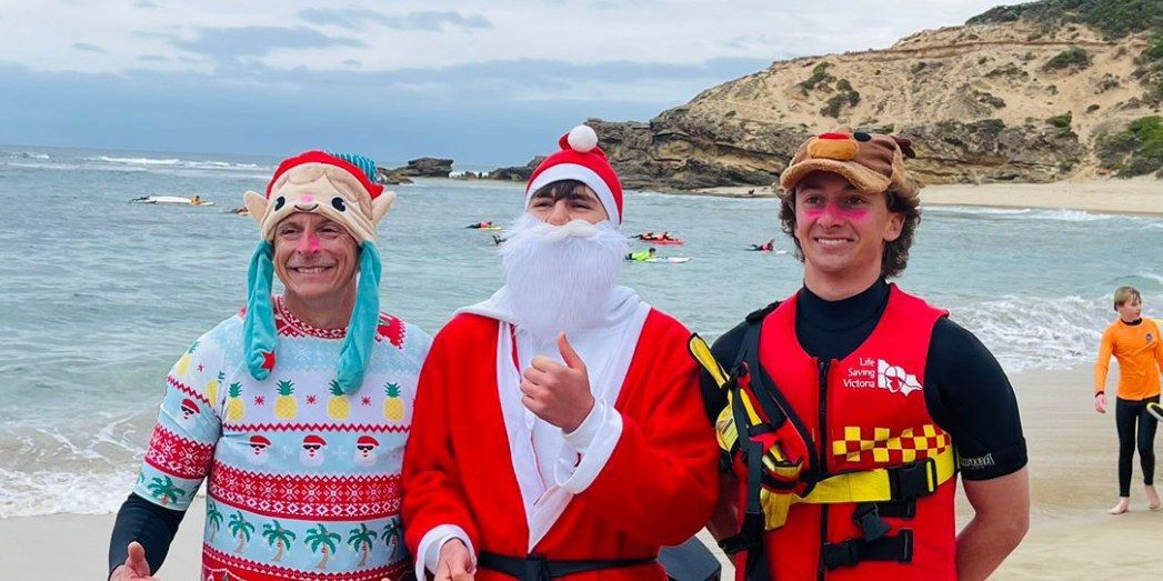 Santa on the beach with two lifesavers after arriving by inflatable rescue boat.