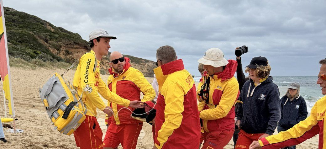 Members and emergency service partners in a training huddle on the beach.