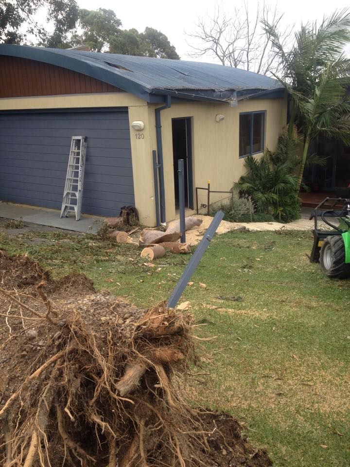 A house with a blue garage door and a pile of logs in front of it.