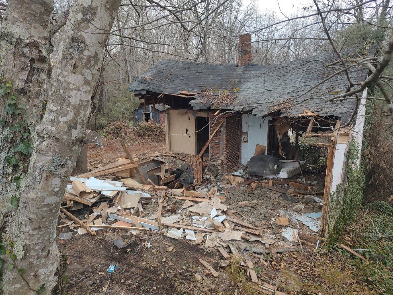 Collapsed, damaged house with rubble and debris in a wooded area