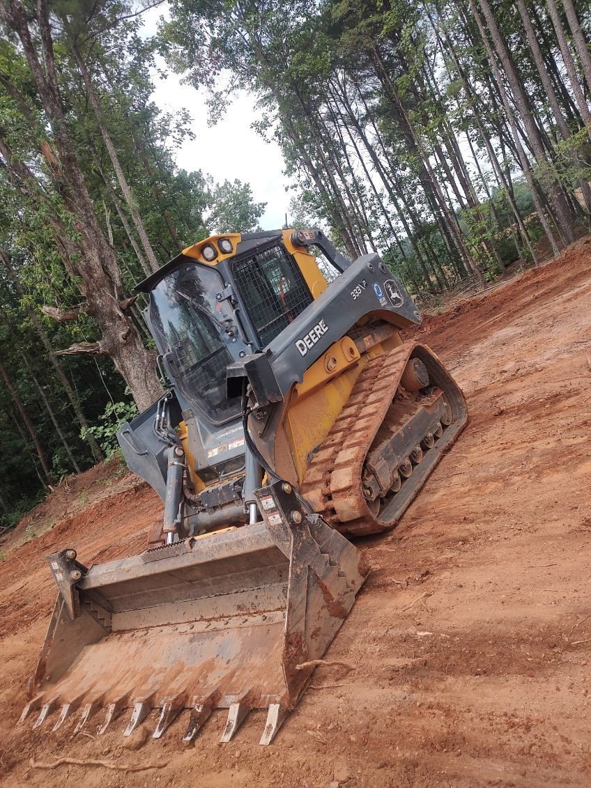 Bulldozer with front blade and tracks on a dirt slope in a wooded area