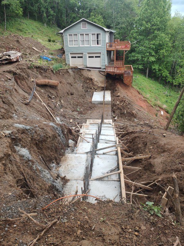 Damaged hillside home with exposed concrete foundation and retaining wall after landslide erosion