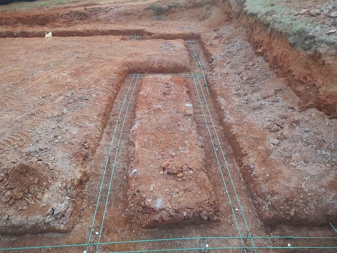 Excavation trench outlined with white markings on a muddy construction site