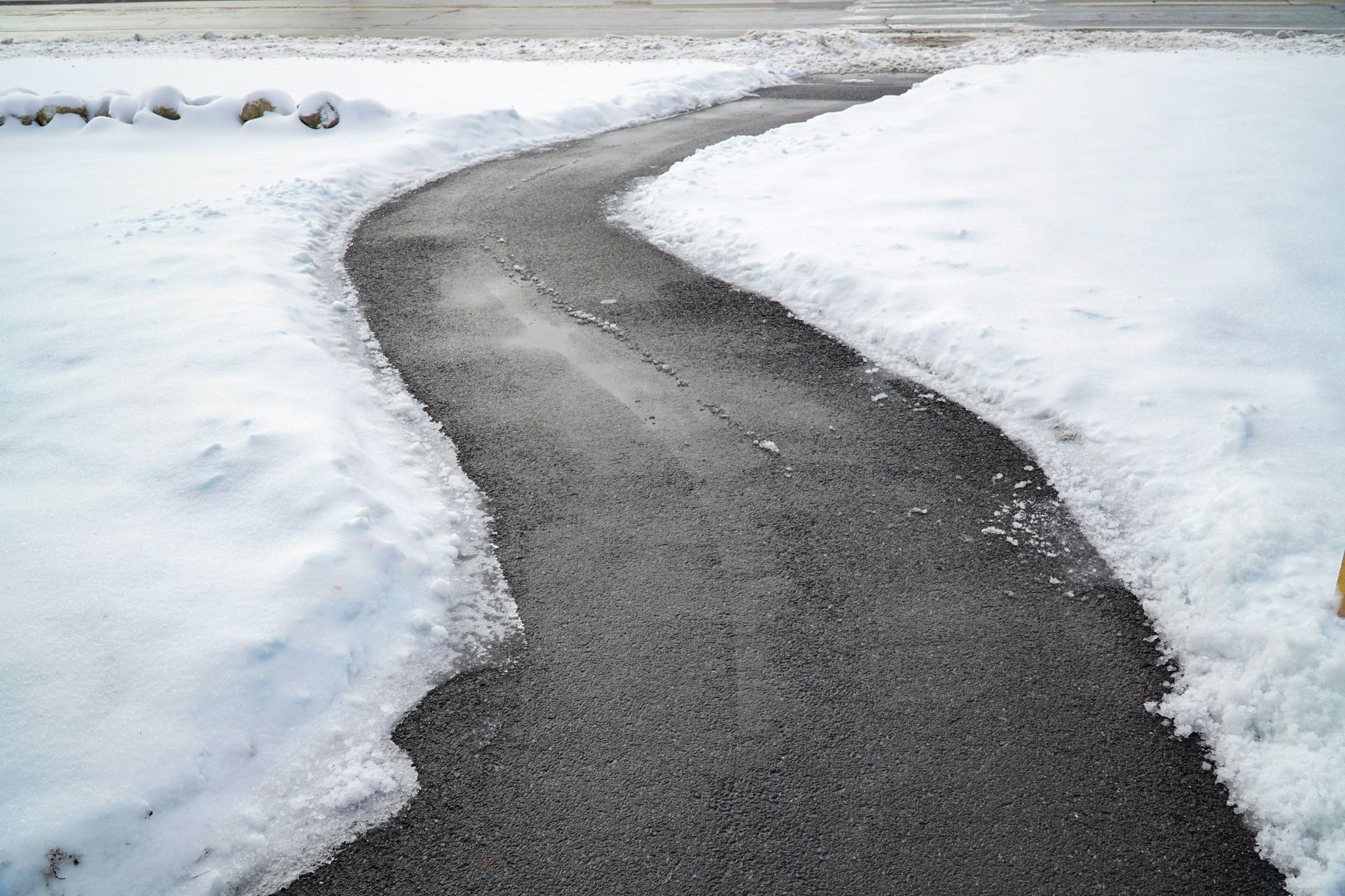 Snow-covered landscape with a narrow winding path clearing through the snow